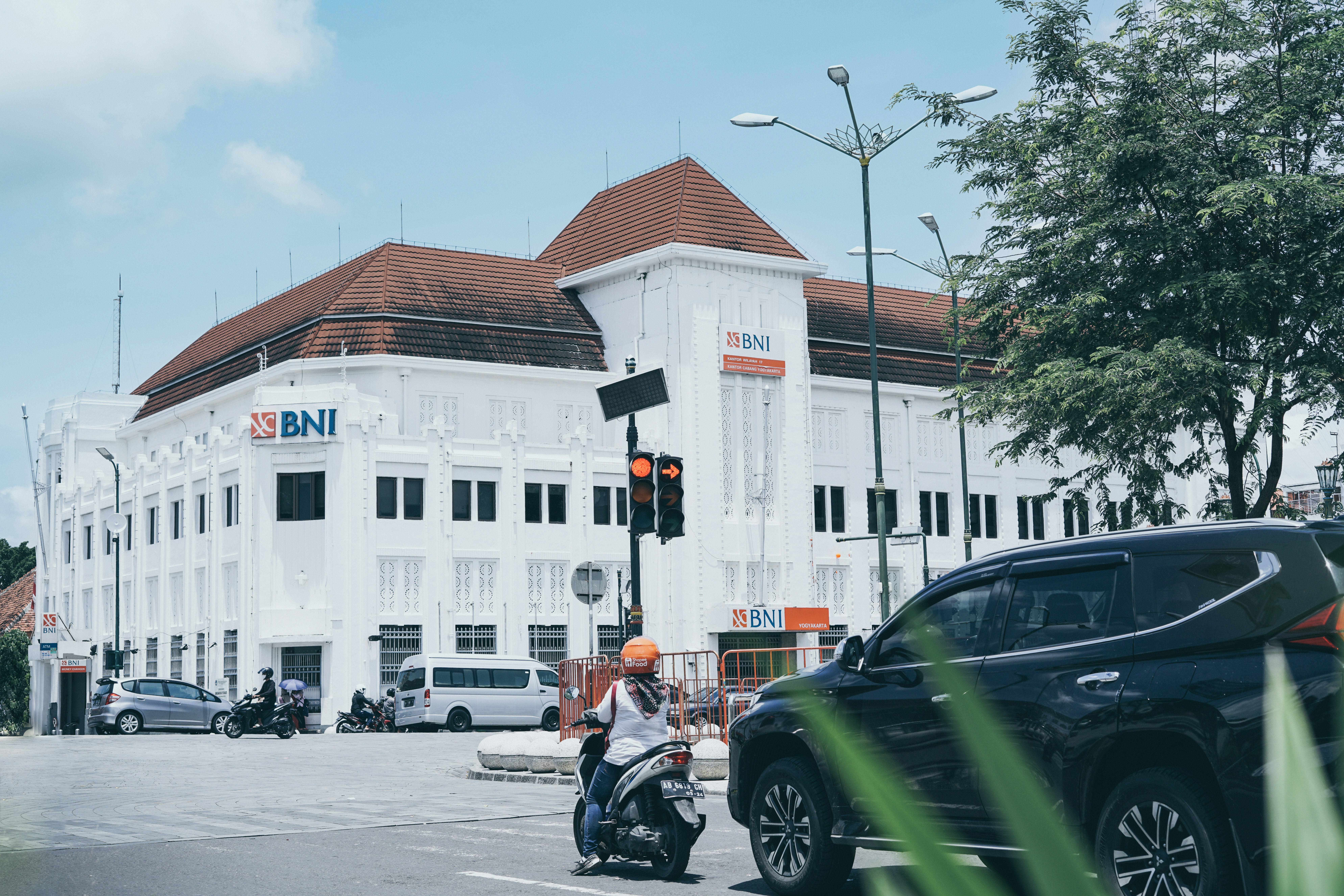 a man riding a motorcycle down a street next to a tall white building