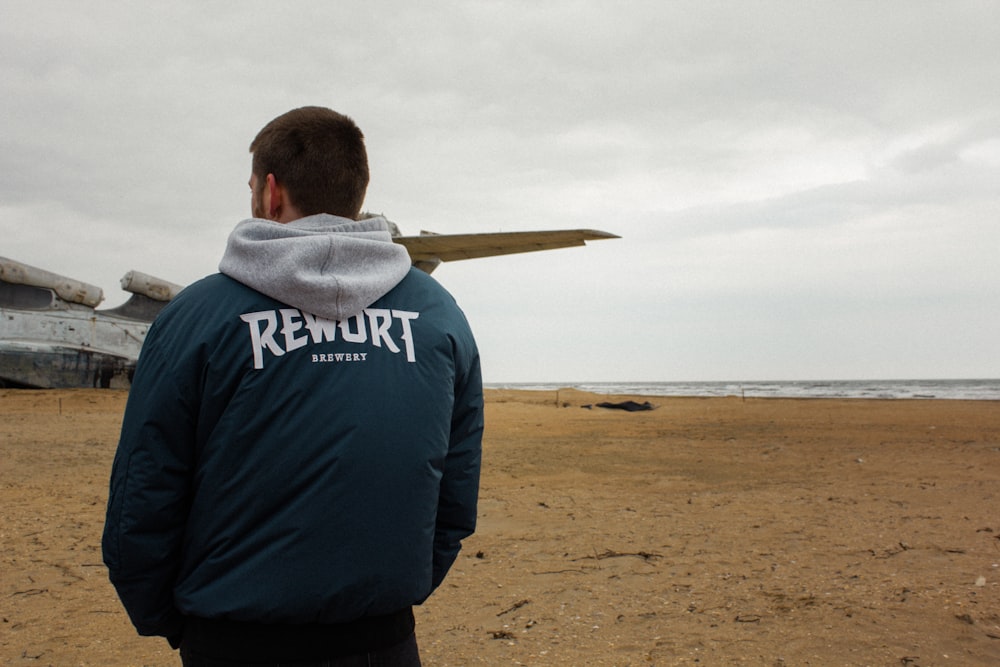 a man standing on a beach next to an airplane