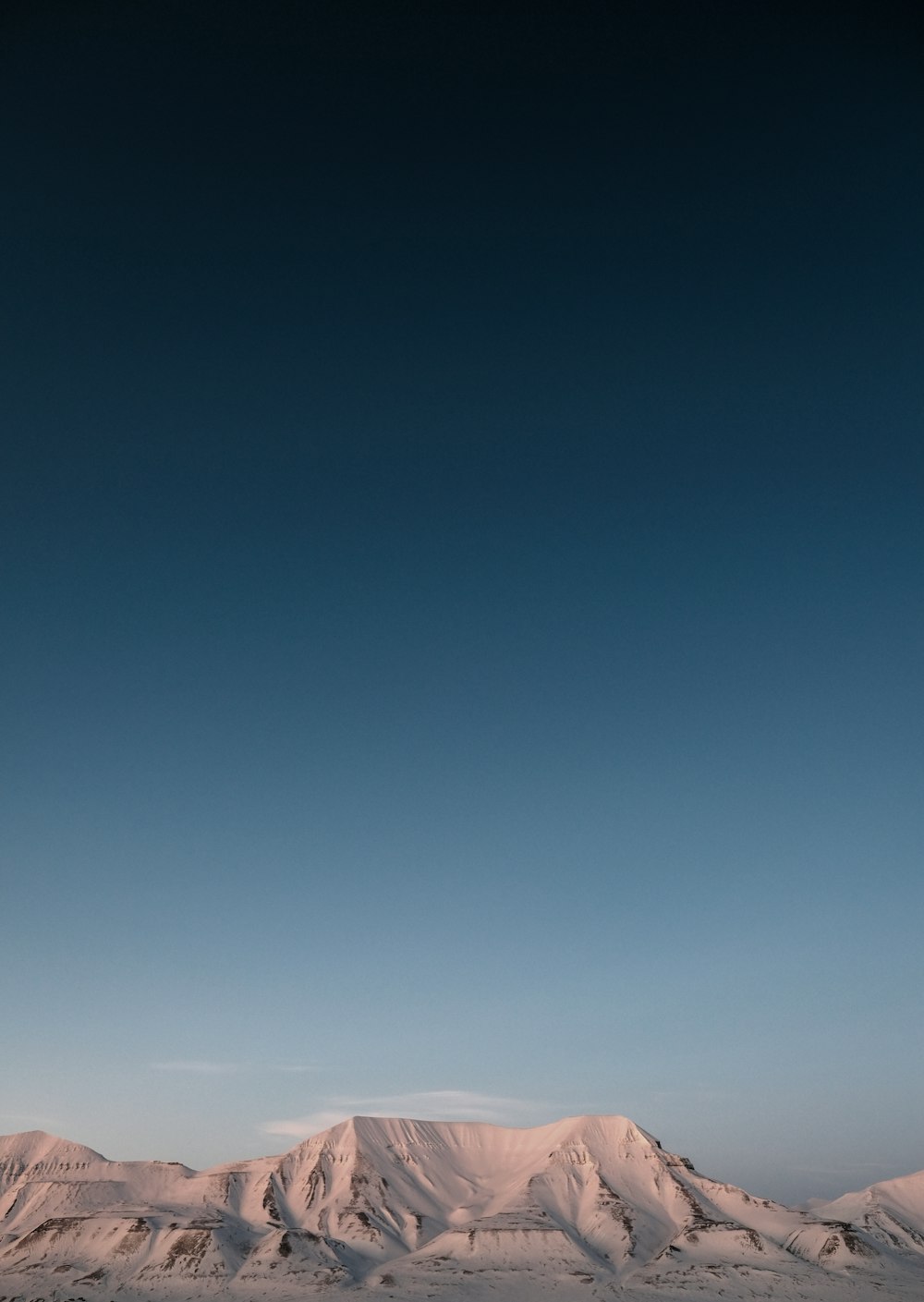 a snow covered mountain range under a blue sky