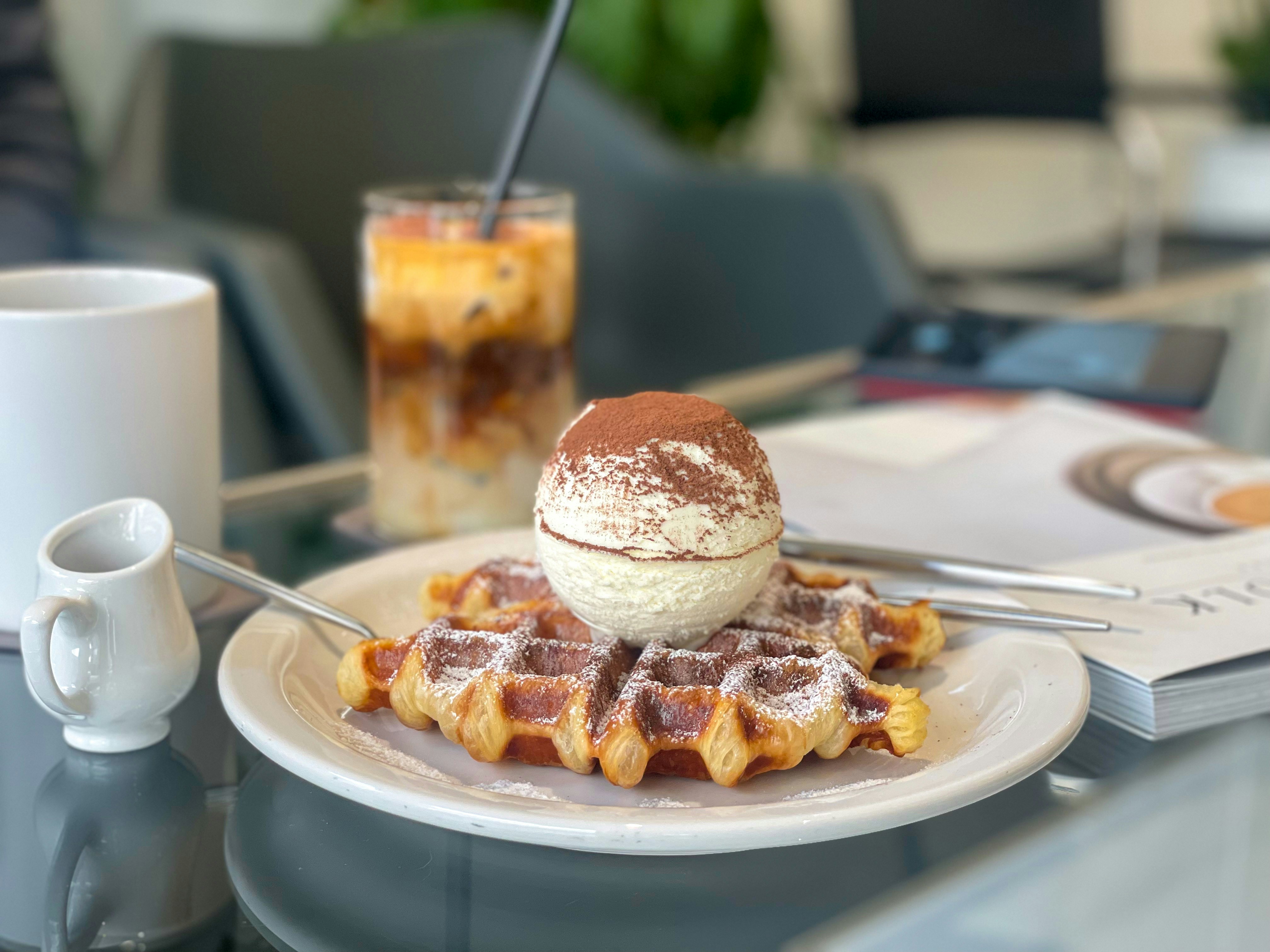 a plate of waffles with a scoop of ice cream on top