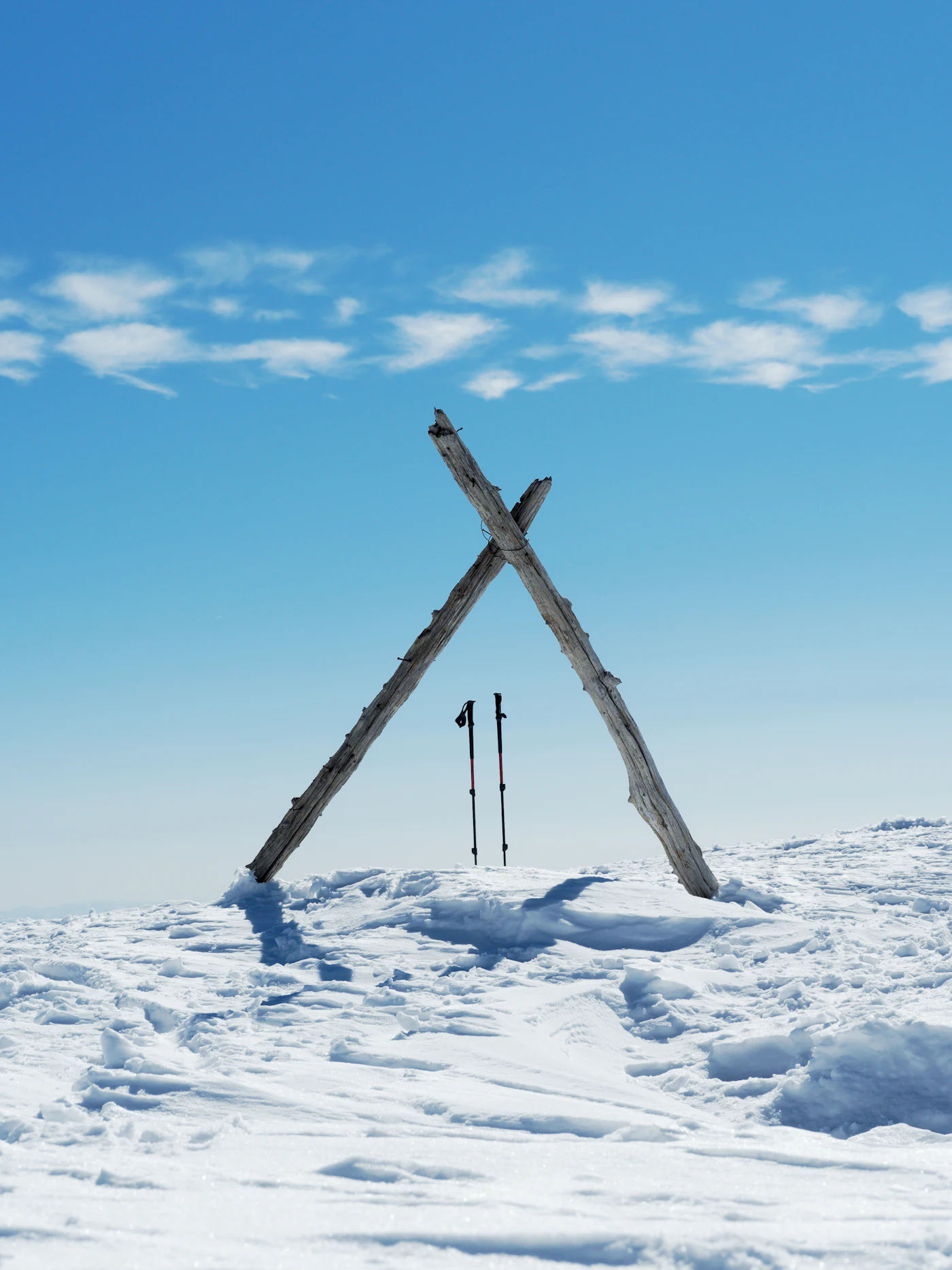 Two trekking poles leaning against a rock overlooking a calm lake