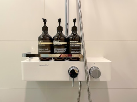 A modern shower rack holding shampoo and soap bottles in a clean shower area.