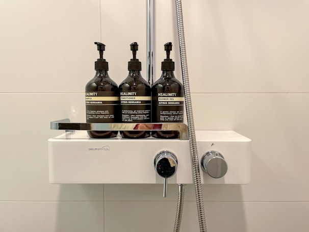 Clear acrylic shower caddy holding shampoo and soap bottles in a modern shower