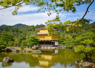 a yellow building in the middle of a pond