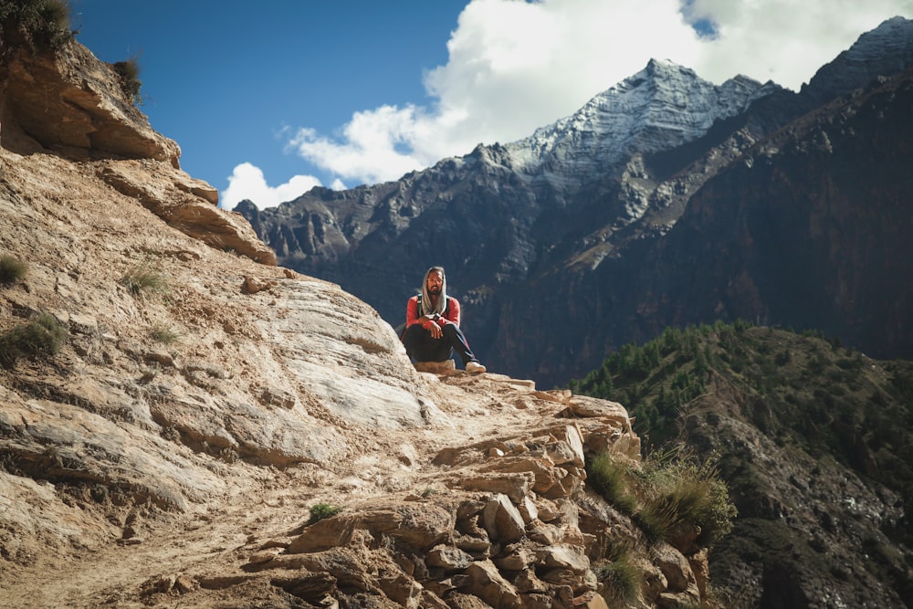 a man sitting on top of a rocky cliff