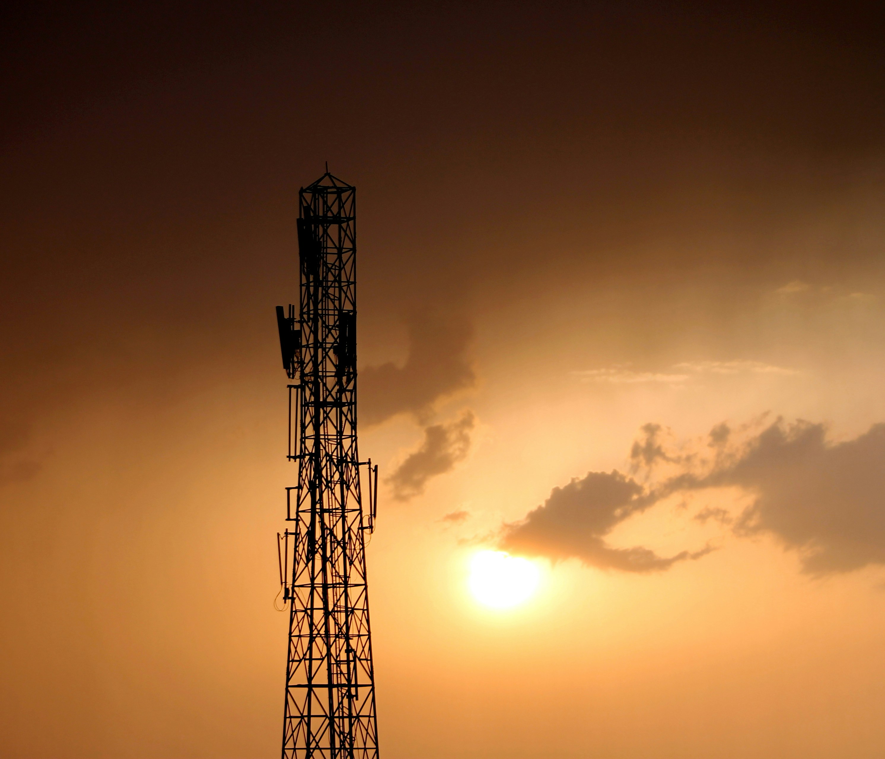 the sun is setting behind a tall tower