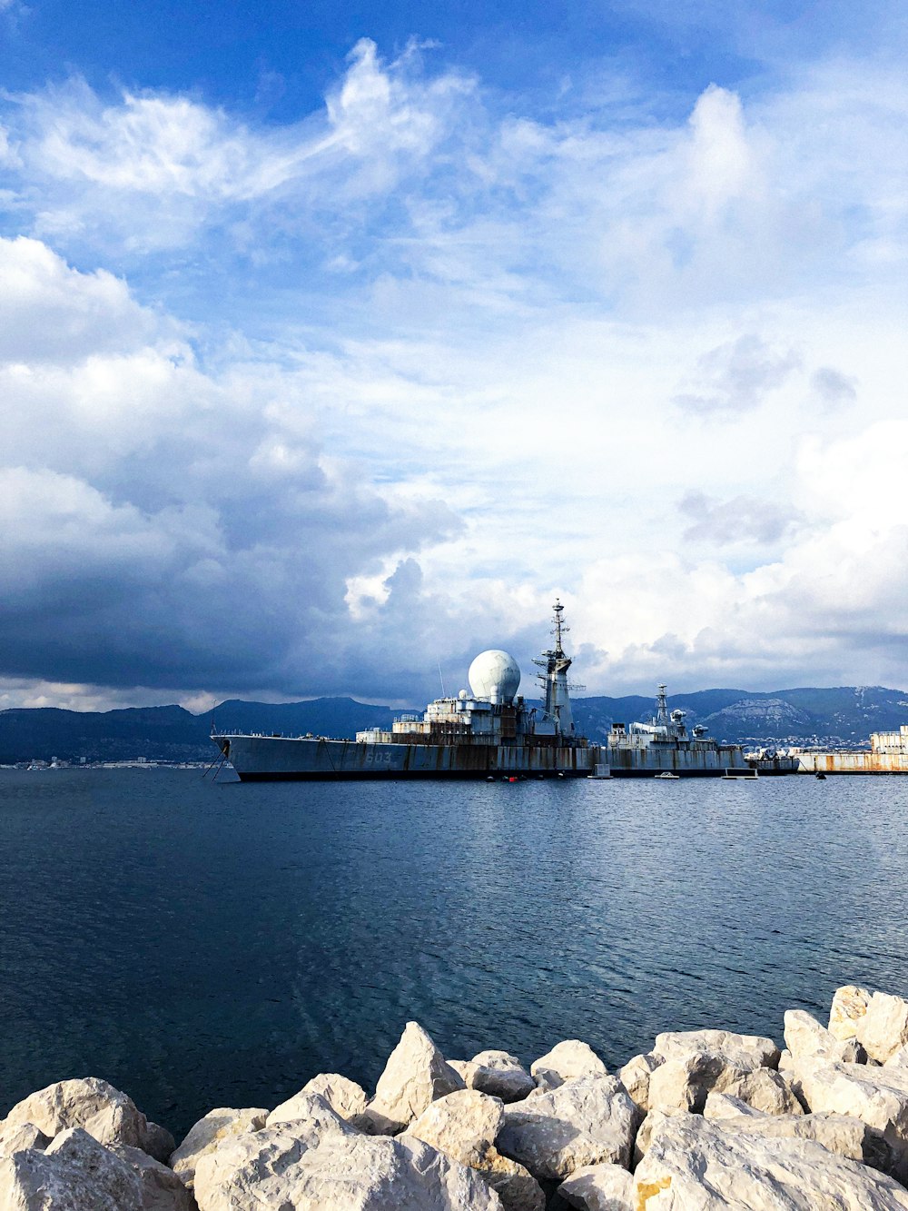 a large ship in the water near some rocks