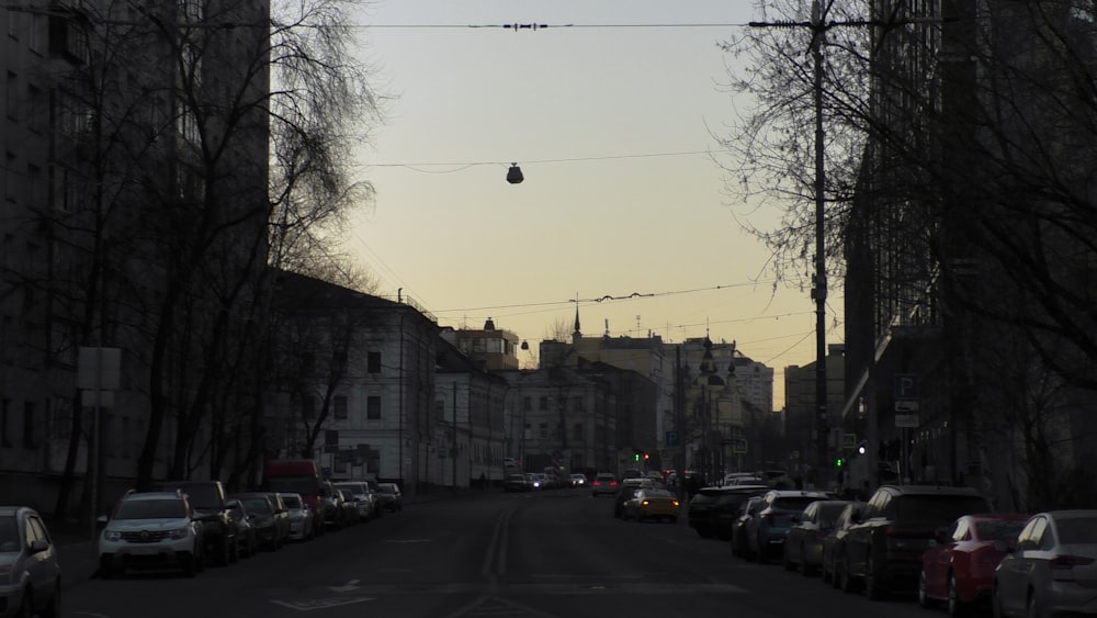 a street filled with lots of parked cars next to tall buildings