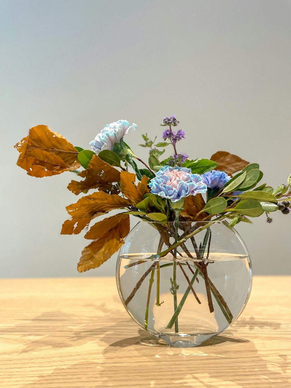 a glass vase filled with flowers on top of a wooden table