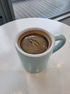 A vibrant ceramic coffee mug with rich blue glaze sitting on a wooden table bathed in morning light.