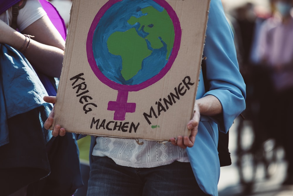 a person holding a cardboard sign with a picture of the earth on it