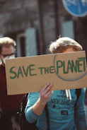 a woman holding a sign that says save the planet