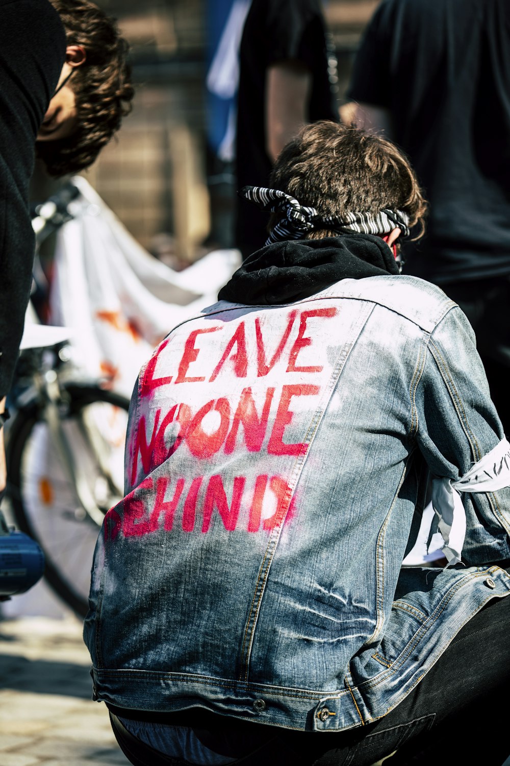 a man sitting on the ground wearing a jean jacket