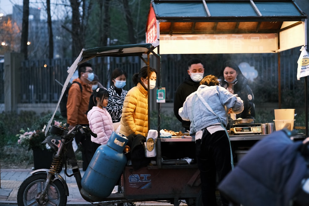 a group of people standing around a food cart