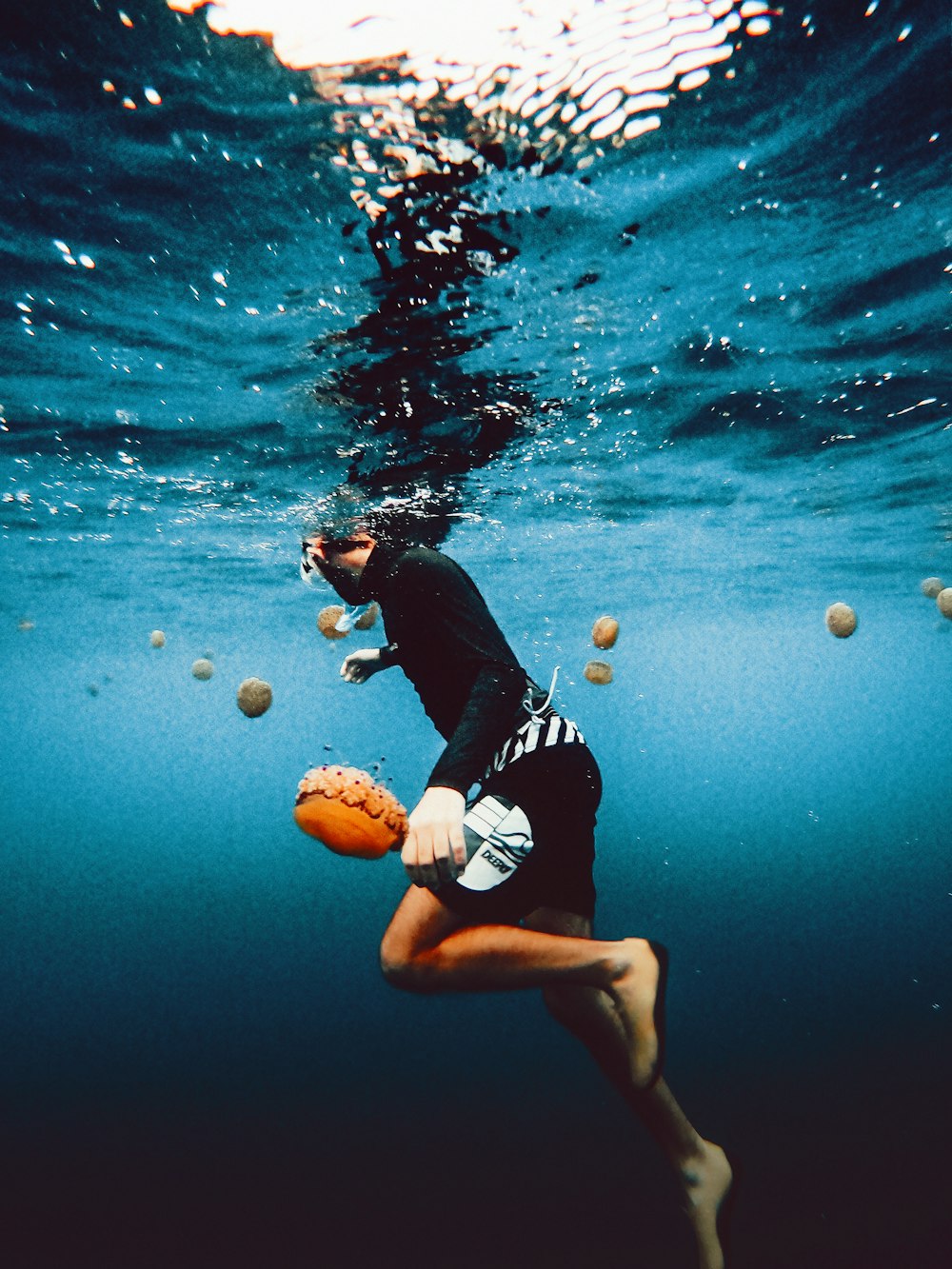 a man in a wet suit holding a ball under water