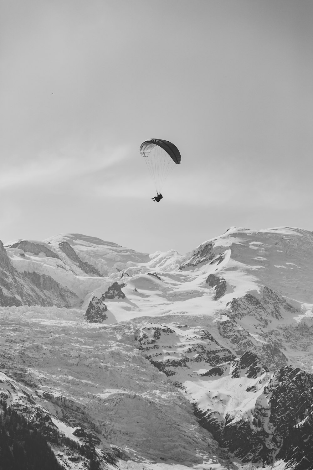a paraglider is flying over a snowy mountain range