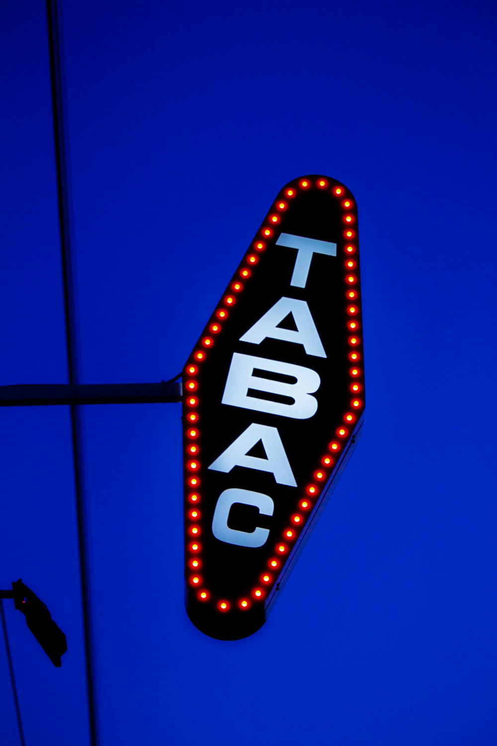 a taco sign lit up against a blue sky