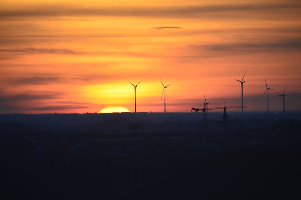 Eine Gruppe von Windmühlen ist eine Silhouette vor einem Sonnenuntergang