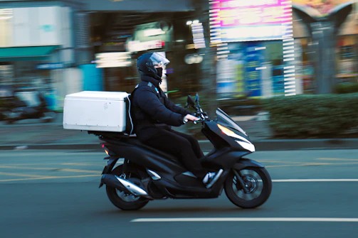 a man riding a scooter with a box on the back of it