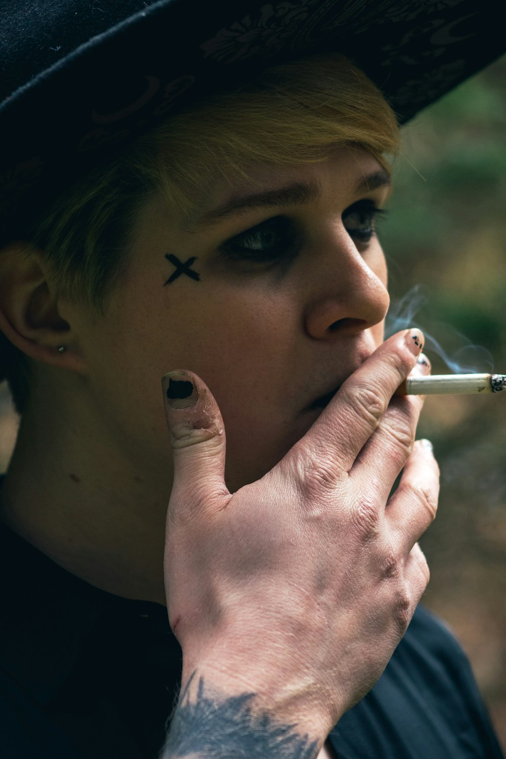 a woman smoking a cigarette with a cross on her forehead