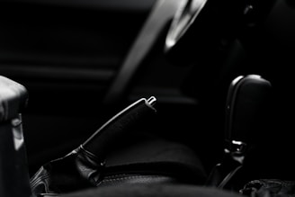 Close-up of a hand gripping a vintage 90s car gearshift, set against a dark, textured metal background.