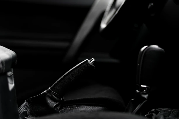 Close-up of a sleek manual gear shifter bathed in moody red and silver lighting inside a car cockpit.