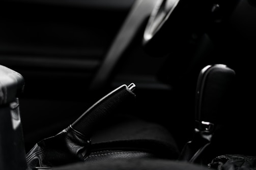 Close-up of a hand gripping a vintage 90s car gearshift, set against a dark, textured metal background.