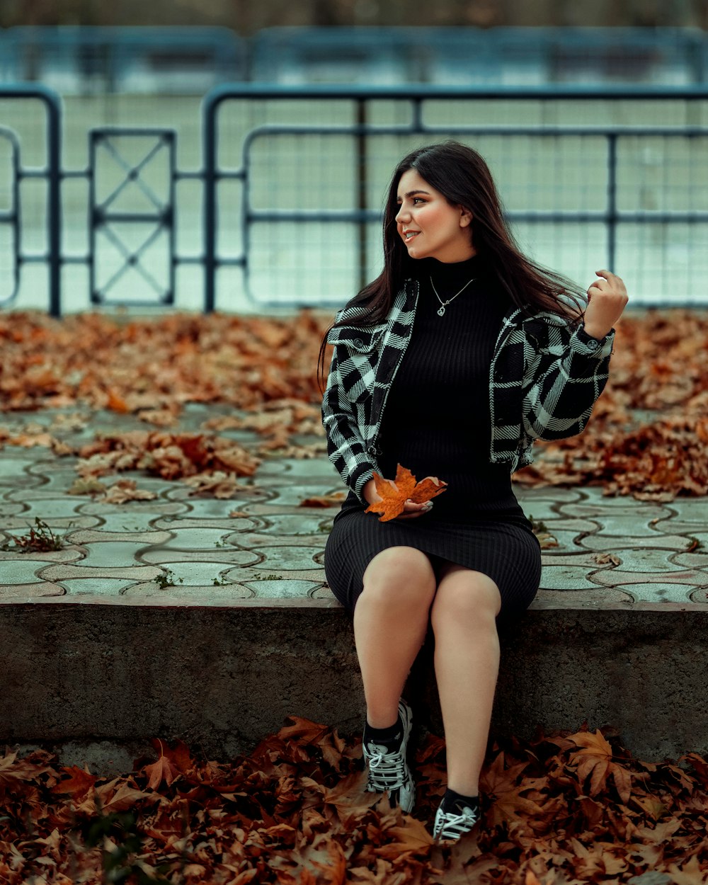 a woman is sitting on a bench in the leaves