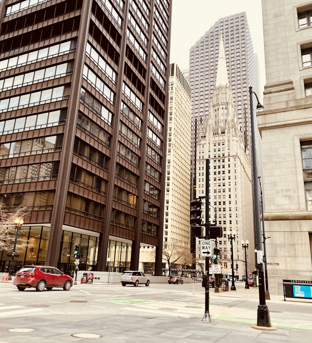 a red car driving down a street next to tall buildings