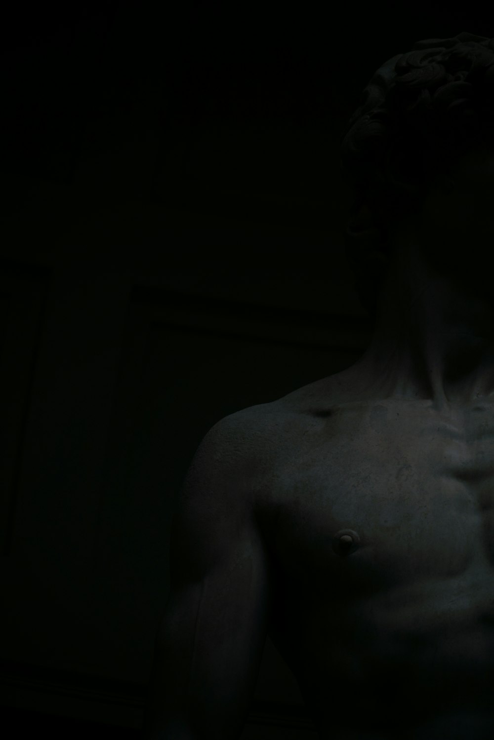 a man with no shirt standing in the dark