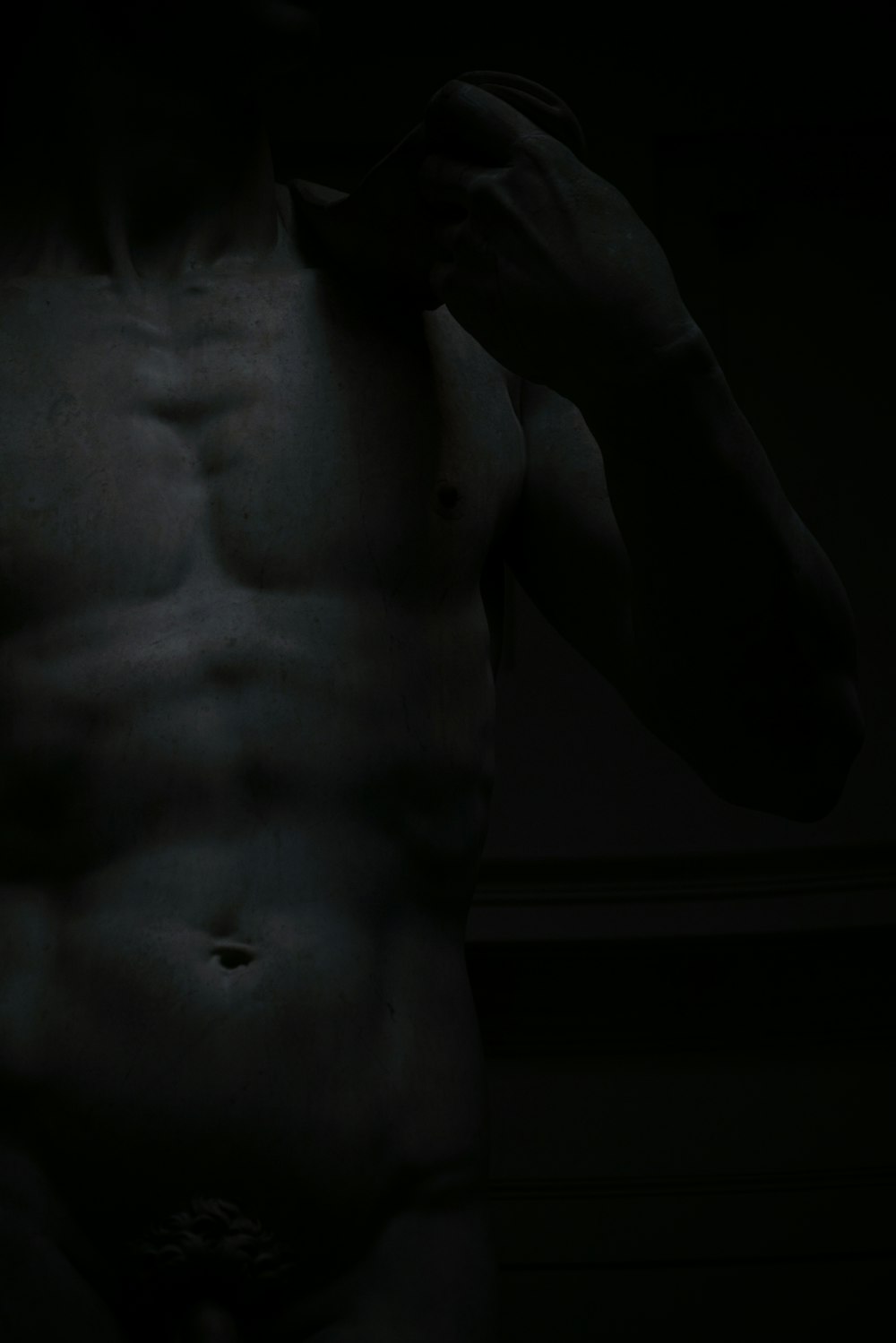 a man without a shirt standing in the dark