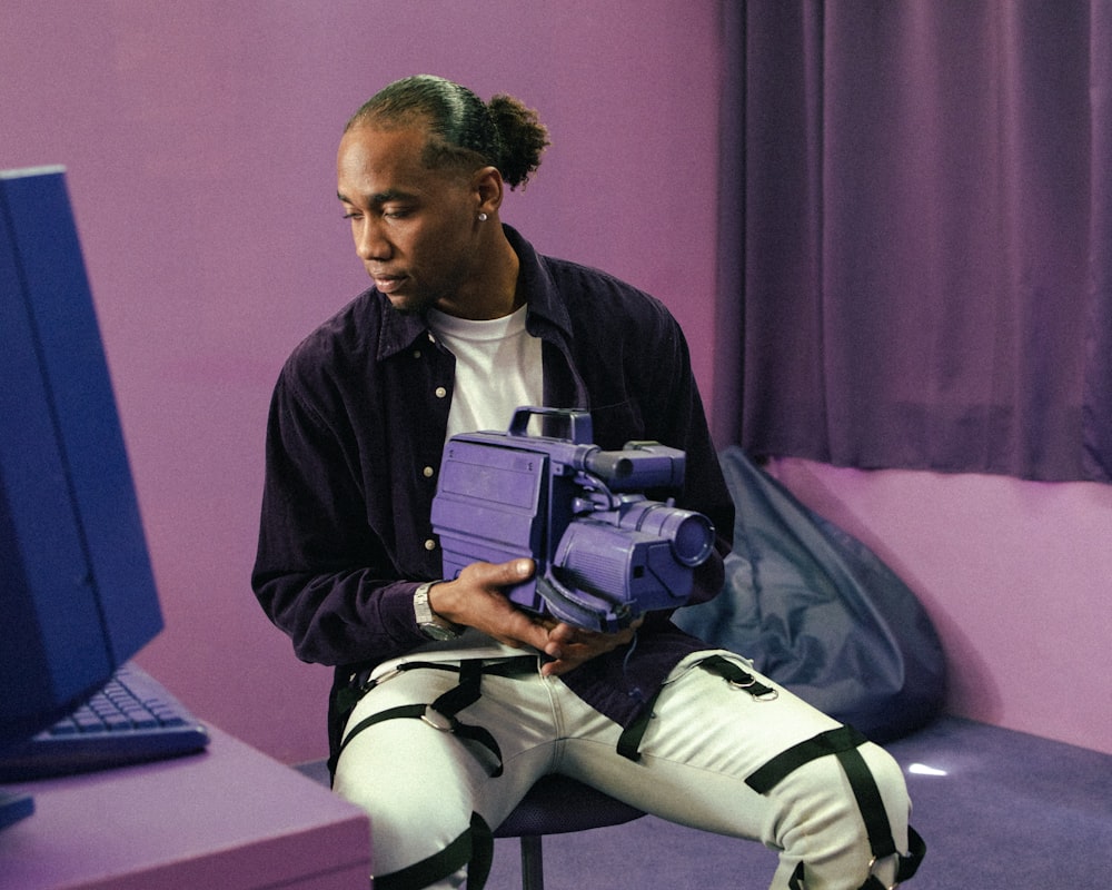 a man sitting in front of a computer holding a purple object