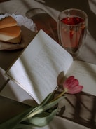 Colorful recipe book pages open on a kitchen table with fresh ingredients nearby