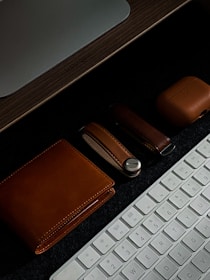 A collection of leather key chains and sleek phone cases arranged on a wooden table.