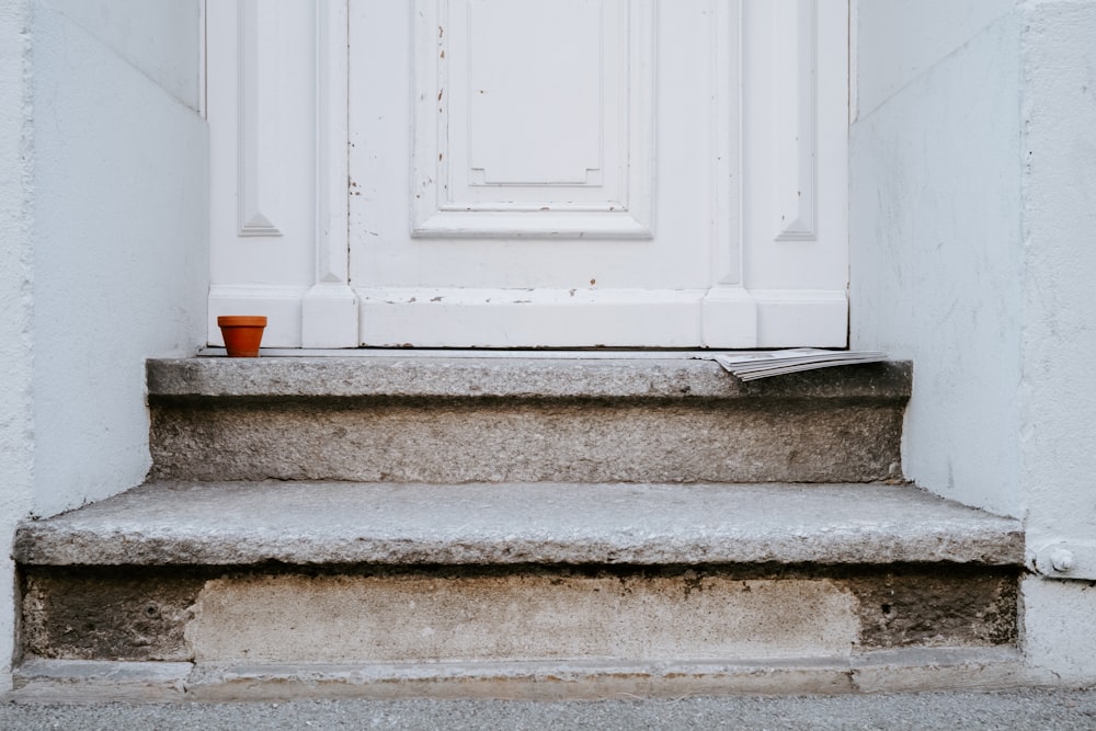 a white door with a red cup on the step