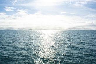 a body of water with the sun shining through the clouds