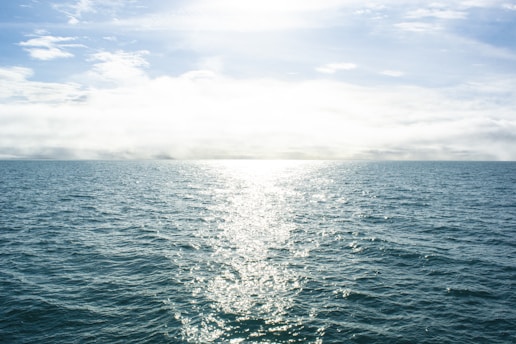 a body of water with the sun shining through the clouds
