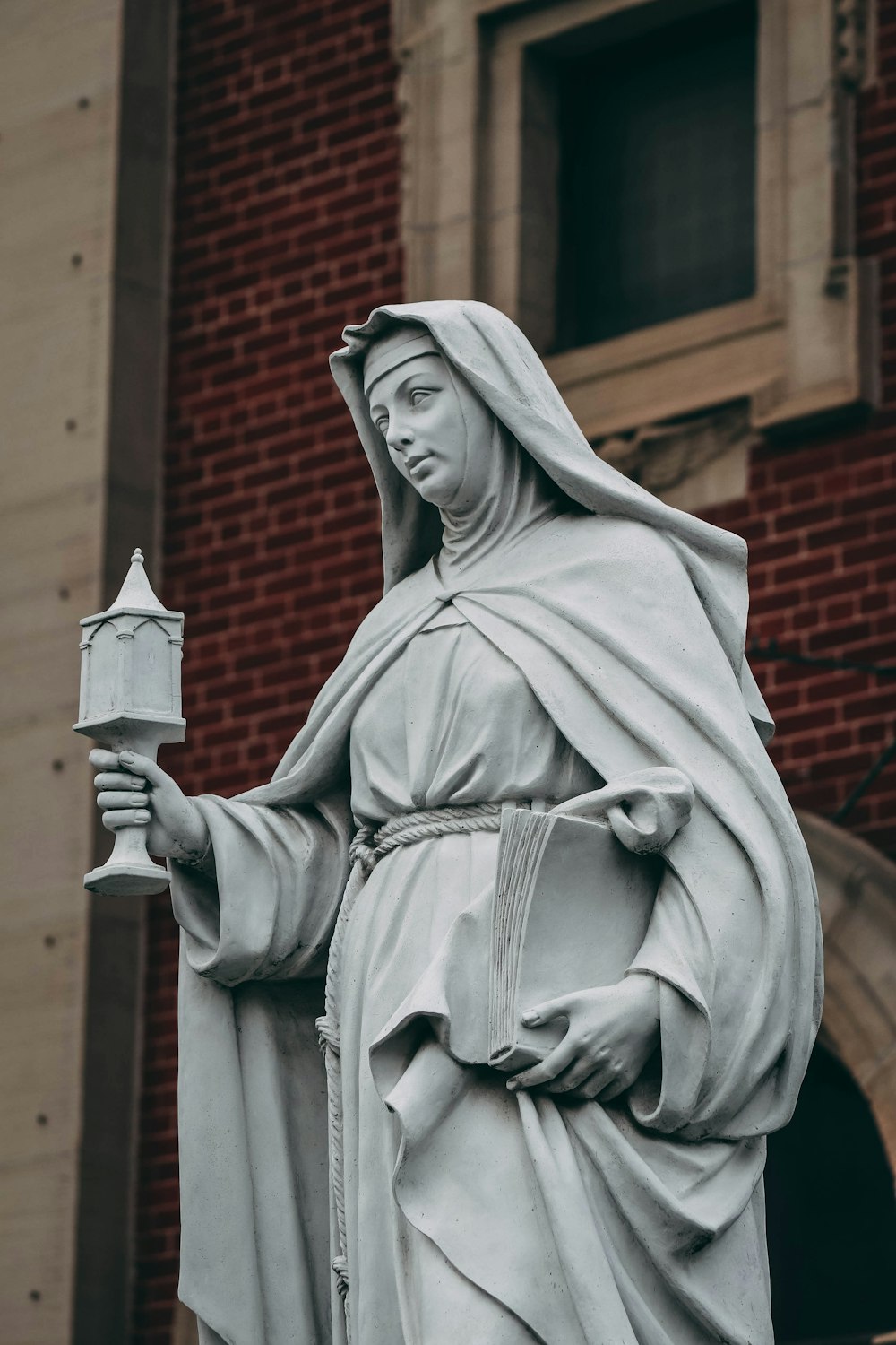 a statue of jesus holding a candle in front of a building