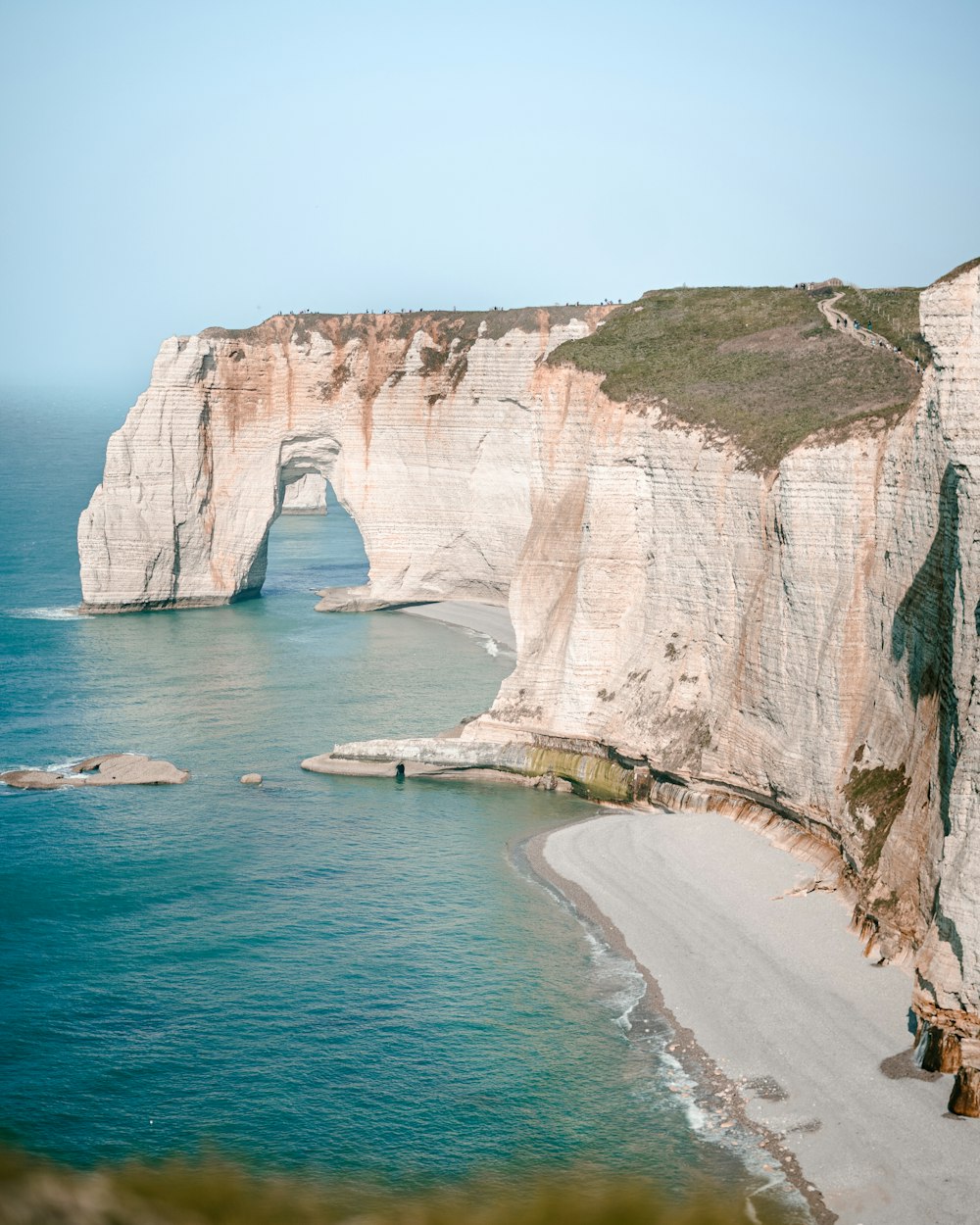 Blick auf einen Strand mit einer großen Felsformation mitten im Ozean