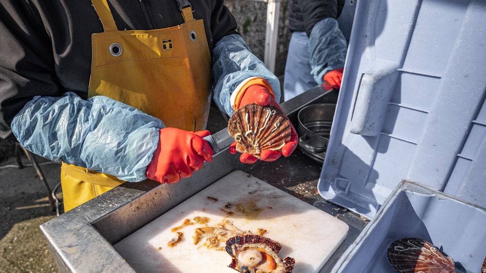 a person in an orange apron is holding a clam