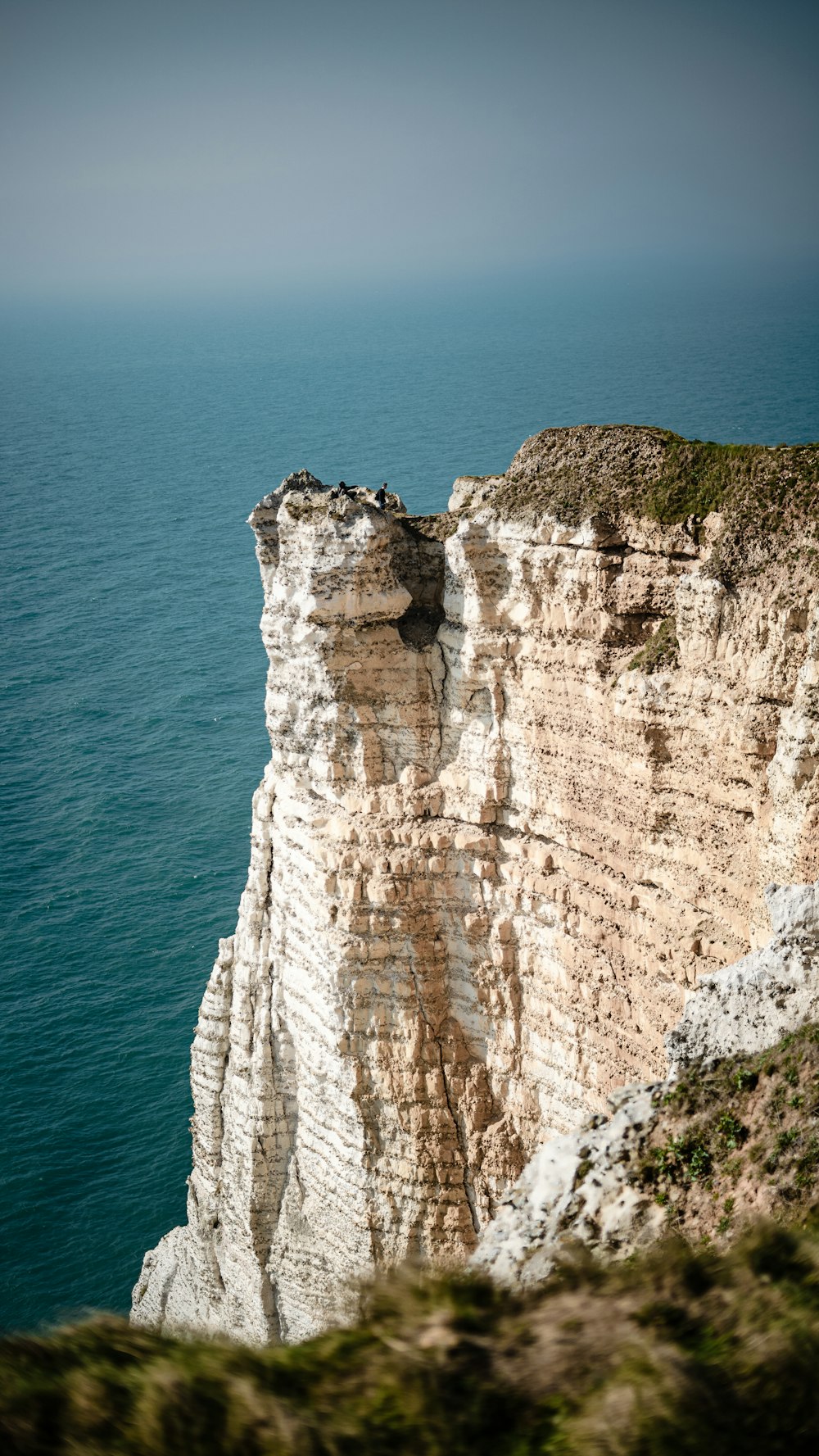 a rocky cliff with a body of water in the background