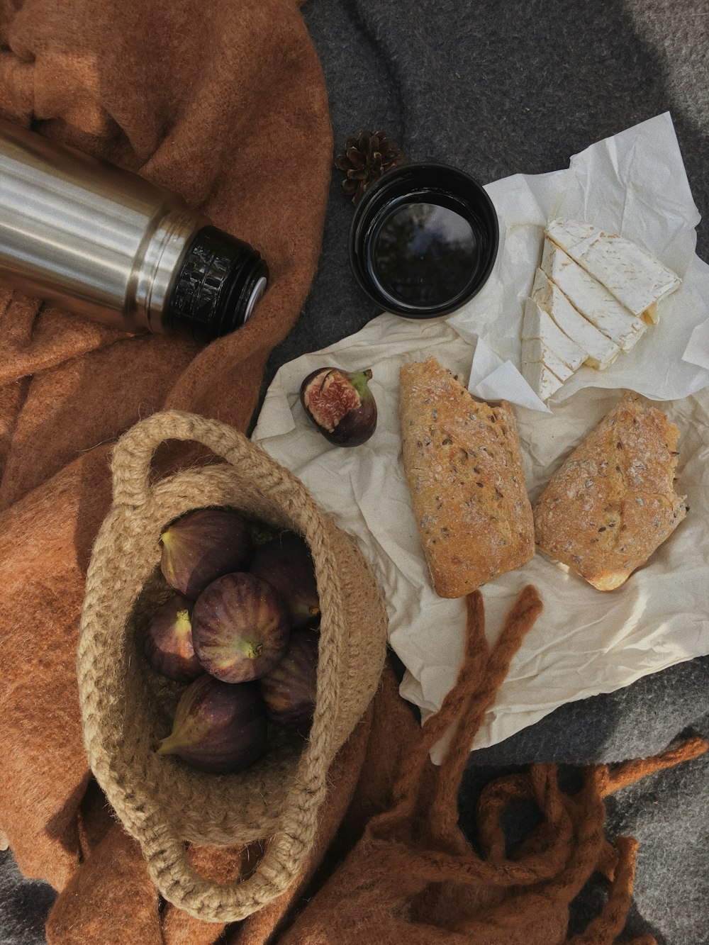 a table topped with bread and figs next to a bottle of wine