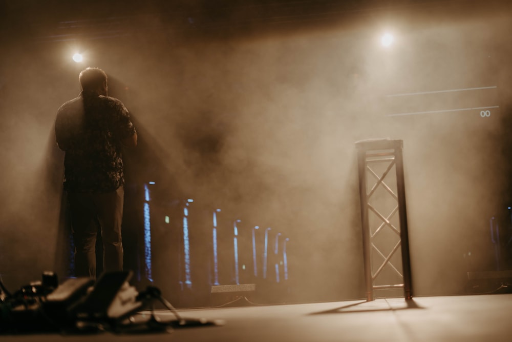 a man standing in front of a stage with fog