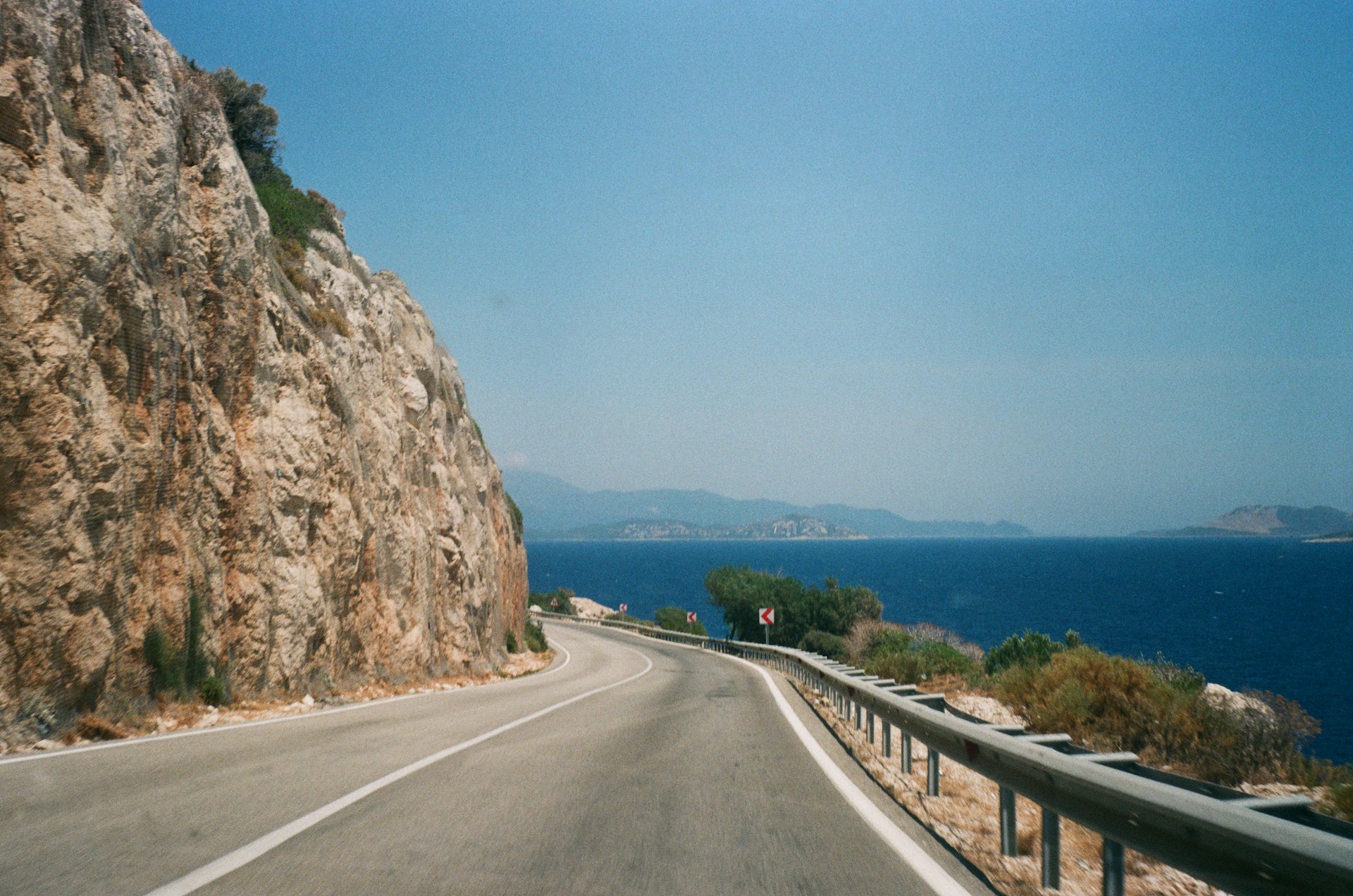 a car driving down a road next to a cliff