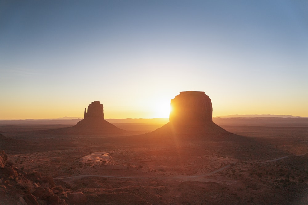 the sun is setting over a desert landscape