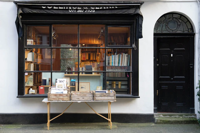A table of books displayed on the pavement in front of a bookshop window