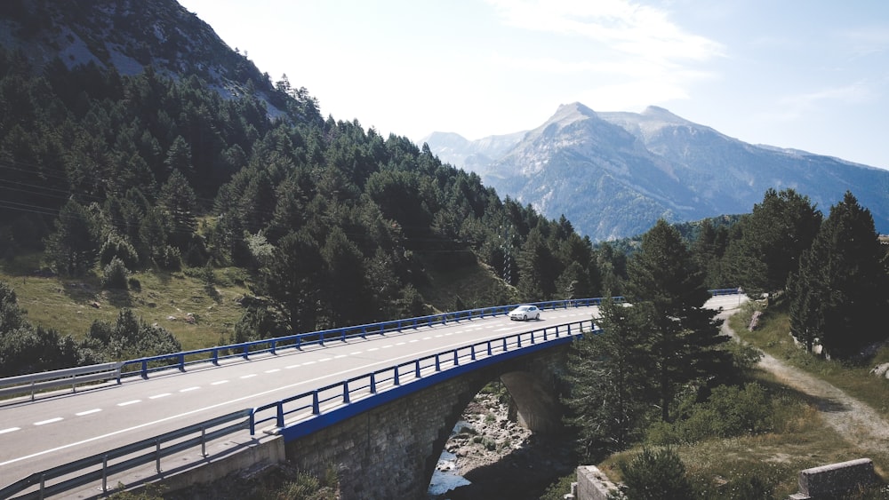 a car driving over a bridge in the mountains