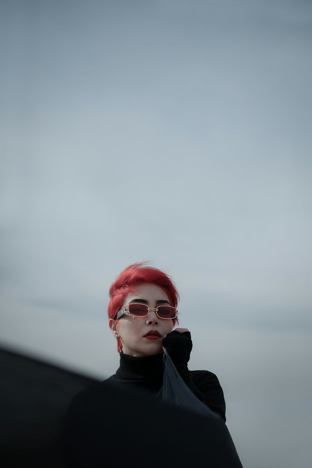 a woman with red hair wearing sunglasses and a black top
