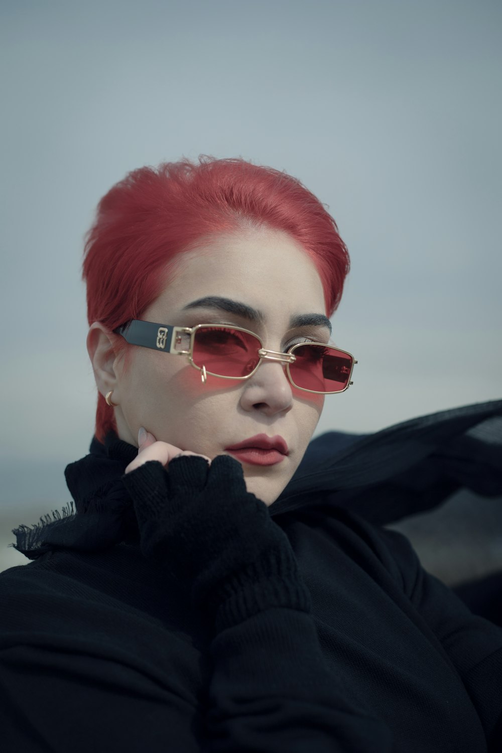 a woman with red hair wearing sunglasses and a black jacket