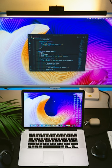 A vibrant snapshot of a desktop with a laptop displaying AI code, headphones, and colorful notebooks around.